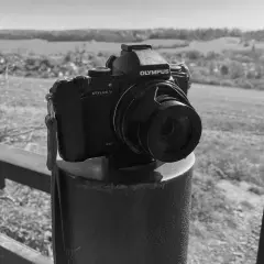 Olympus Stylus 1 camera staat op een paal, klaar om het landschap vast te leggen.
