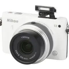 Witte Nikon 1 S2 camera met pop-up flitser en lens.