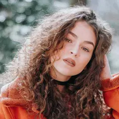 Een portret van een vrouw met krullend haar, die zich afvraagt hoe maak je een foto scherper.