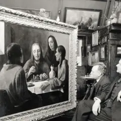 Twee mannen bewonderen een schilderij, mogelijk een van de kunstwerken van Johannes Vermeer, in een kamer vol met andere schilderijen.