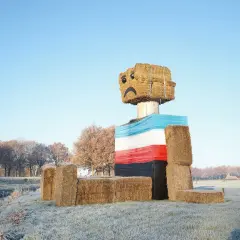 Een vrolijke, met stro gebouwde figuur met een verdrietig gezichtje, een kunstwerk van Henk Wildschut, staat in een winterse wei.