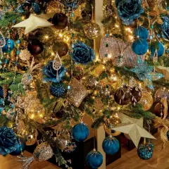 Een kerstboom vol met blauw goud, glinsterende ornamenten, blauwe bloemen en gouden sterren.