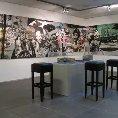 Een muurschildering met jazzmuzikanten en surrealistische elementen, mogelijk van Hans Truijen, in een galerie met barkrukken.
