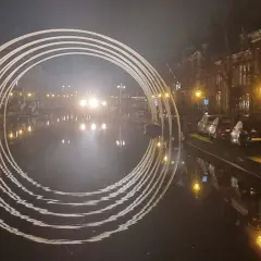 Een verlichte boog over een gracht in Leiden, met reflecties in het water. Dit is een prachtig staaltje kunst in Leiden.