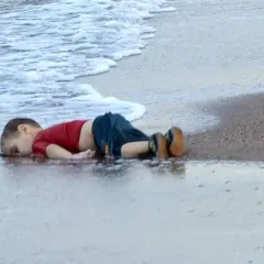 Een jongetje ligt op het strand, met zijn gezicht in het water. Wat is een foto van een kind dat geniet van de zee.