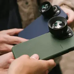 Twee personen houden iPhones vast met externe lenzen, klaar om te fotograferen met hun iPhone.