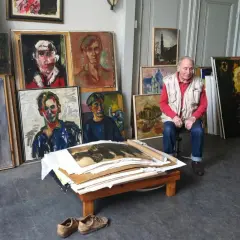 Jan Sierhuis, omringd door zijn kleurrijke portretten en stadsgezichten, in zijn atelier.