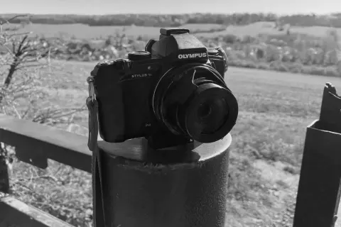 Olympus Stylus 1 camera staat op een paal, klaar om het landschap vast te leggen.