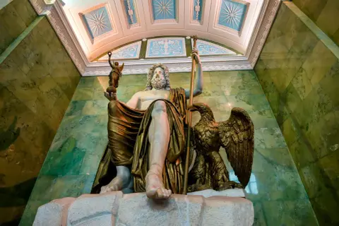 Zittende Zeus, de Romeinse naam is Jupiter, met adelaar en Nikè. Groene marmeren muren en een versierd plafond.