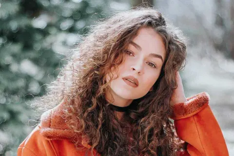 Een portret van een vrouw met krullend haar, die zich afvraagt hoe maak je een foto scherper.