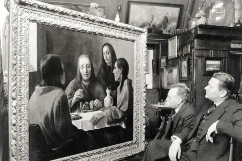 Twee mannen bewonderen een schilderij, mogelijk een van de kunstwerken van Johannes Vermeer, in een kamer vol met andere schilderijen.