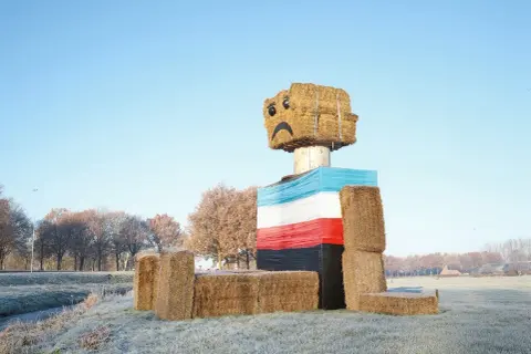 Een vrolijke, met stro gebouwde figuur met een verdrietig gezichtje, een kunstwerk van Henk Wildschut, staat in een winterse wei.