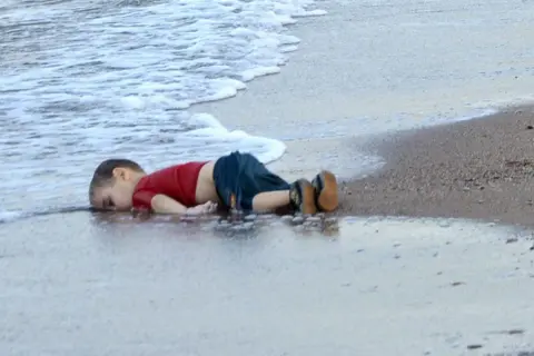 Een jongetje ligt op het strand, met zijn gezicht in het water. Wat is een foto van een kind dat geniet van de zee.