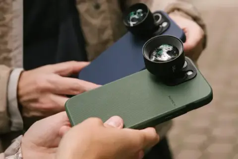 Twee personen houden iPhones vast met externe lenzen, klaar om te fotograferen met hun iPhone.