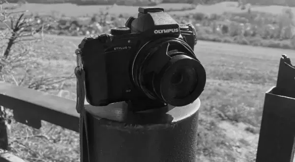 Olympus Stylus 1 camera staat op een paal, klaar om het landschap vast te leggen.