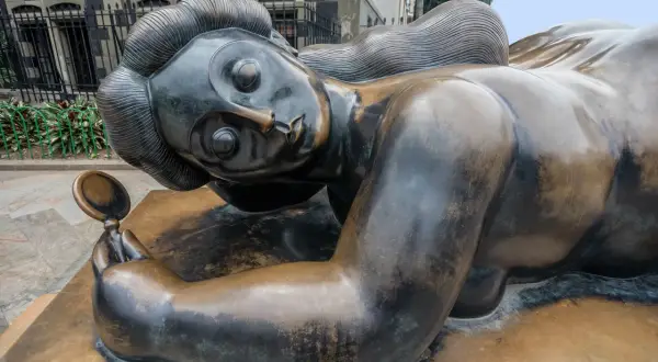 Bronzen beeld van een liggende vrouw met spiegel, een iconisch werk van een bekende beeldhouwer.