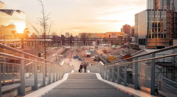 Twee mannen lopen een trap af in Utrecht, met op de achtergrond een bouwterrein en moderne gebouwen. Mooie foto locaties Utrecht.