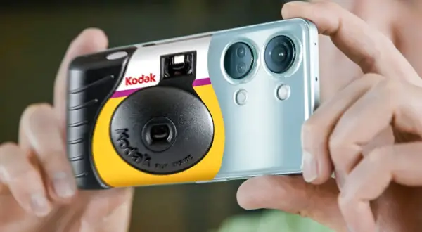 Een Kodak wegwerpcamera wordt vastgehouden naast een smartphone. Dit toont hoe werkt een wegwerpcamera: simpel en direct.