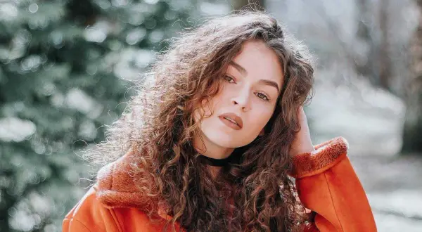 Een portret van een vrouw met krullend haar, die zich afvraagt hoe maak je een foto scherper.