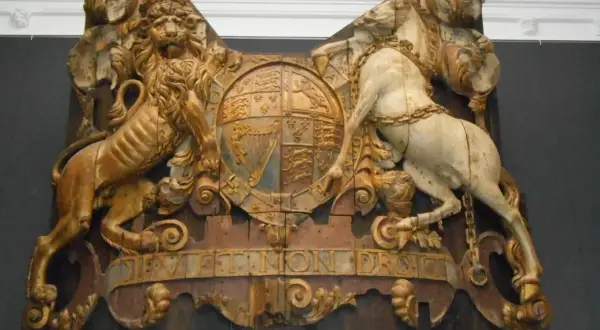 Gouden leeuw en wit paard houden een wapenschild vast, met de tekst "Dieu et mon droit". Een koninklijk pronkstuk, mogelijk van de spiegel Royal Charles.