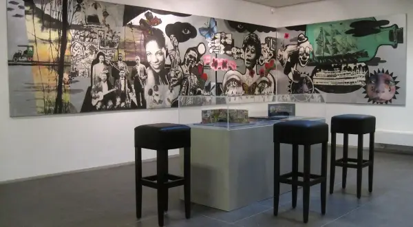 Een muurschildering met jazzmuzikanten en surrealistische elementen, mogelijk van Hans Truijen, in een galerie met barkrukken.