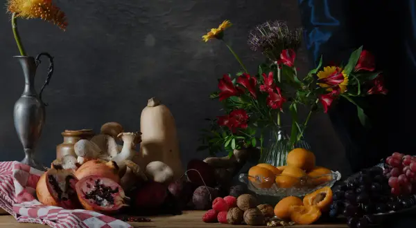 Een rijke **still life** met fruit, groenten, paddenstoelen en bloemen op een houten tafel.