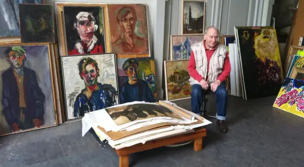 Jan Sierhuis, omringd door zijn kleurrijke portretten en stadsgezichten, in zijn atelier.