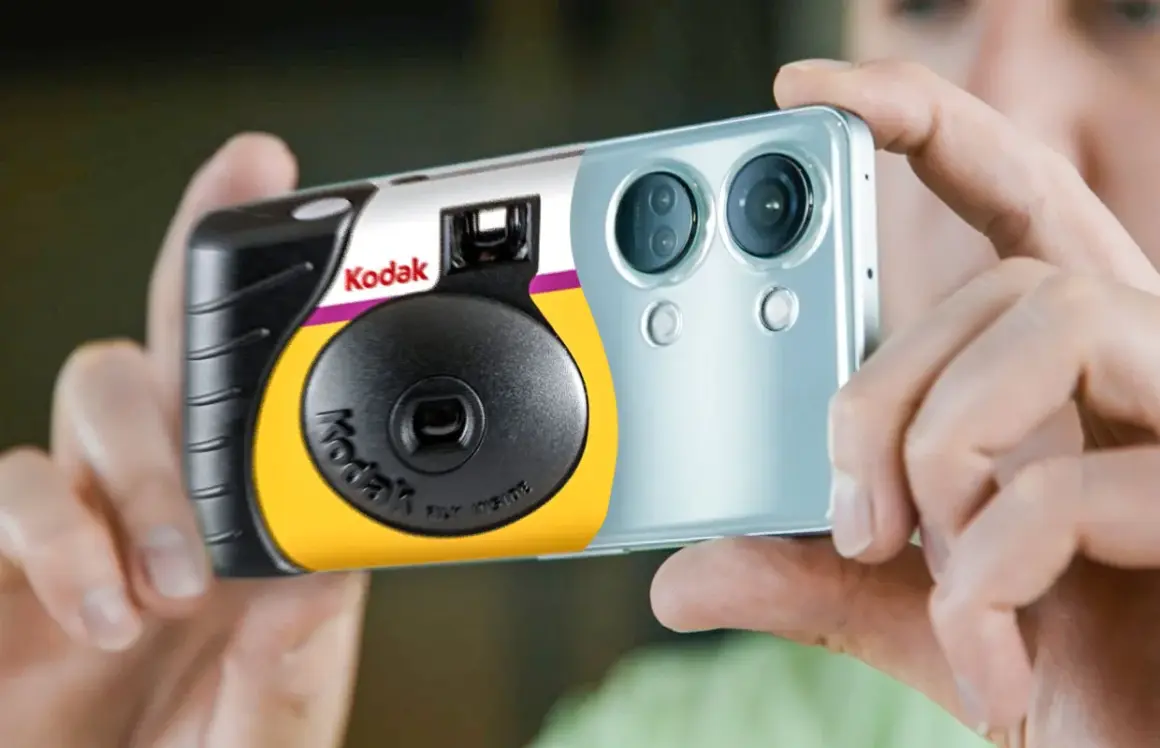 Een Kodak wegwerpcamera wordt vastgehouden naast een smartphone. Dit toont hoe werkt een wegwerpcamera: simpel en direct.