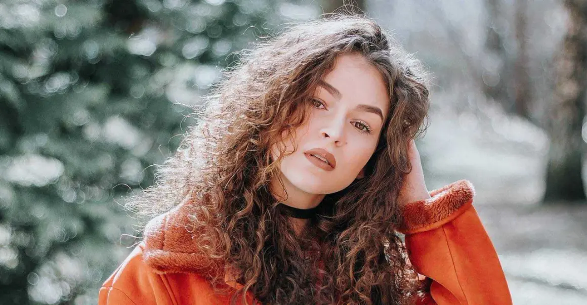Een portret van een vrouw met krullend haar, die zich afvraagt hoe maak je een foto scherper.