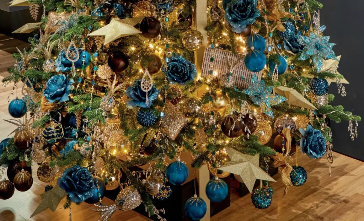 Een kerstboom vol met blauw goud, glinsterende ornamenten, blauwe bloemen en gouden sterren.
