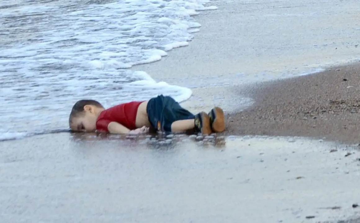 Een jongetje ligt op het strand, met zijn gezicht in het water. Wat is een foto van een kind dat geniet van de zee.