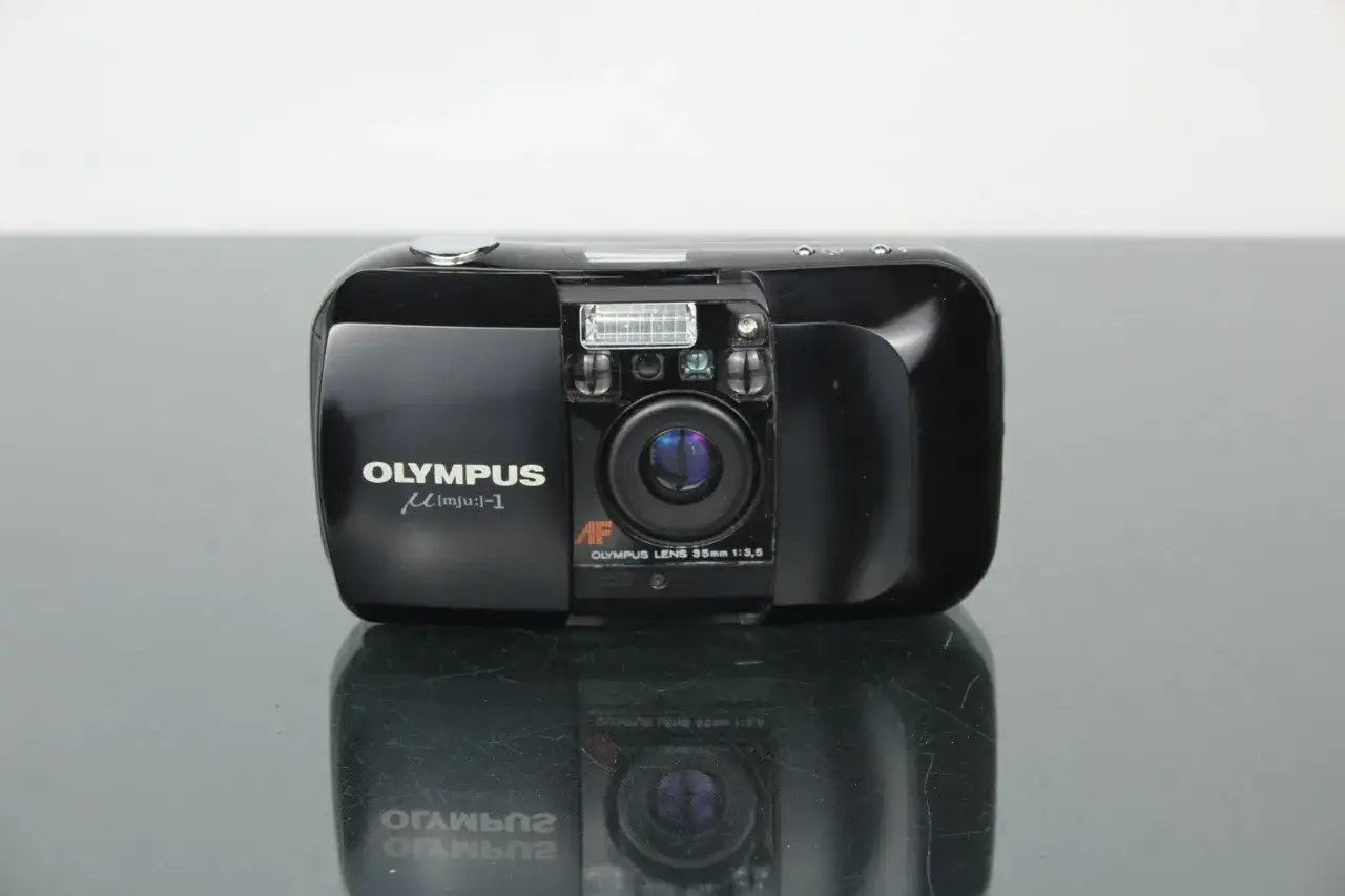 Zwarte Olympus mju: 1 compactcamera met lens en flitser, klaar om nostalgische momenten vast te leggen.