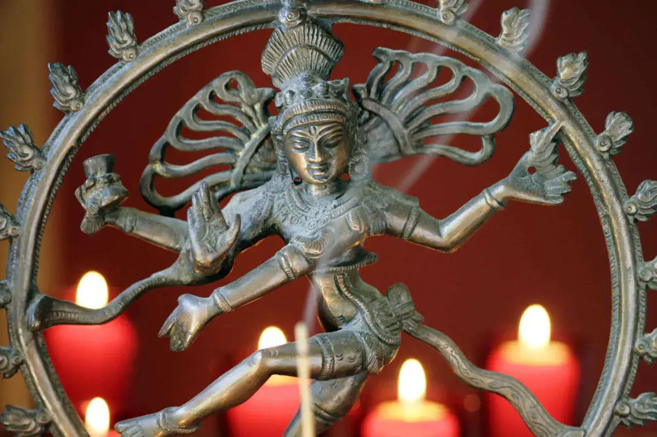 Bronzen beeld van Shiva Nataraja, de dansende god uit het hindoe&iuml;sme, omringd door brandende kaarsen.