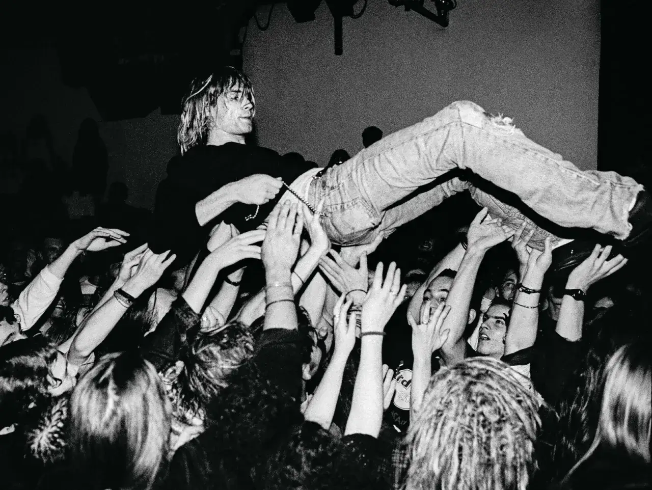 Een menigte draagt een zanger, vastgelegd door paul bergen fotograaf. De zanger zweeft boven de handen van fans.