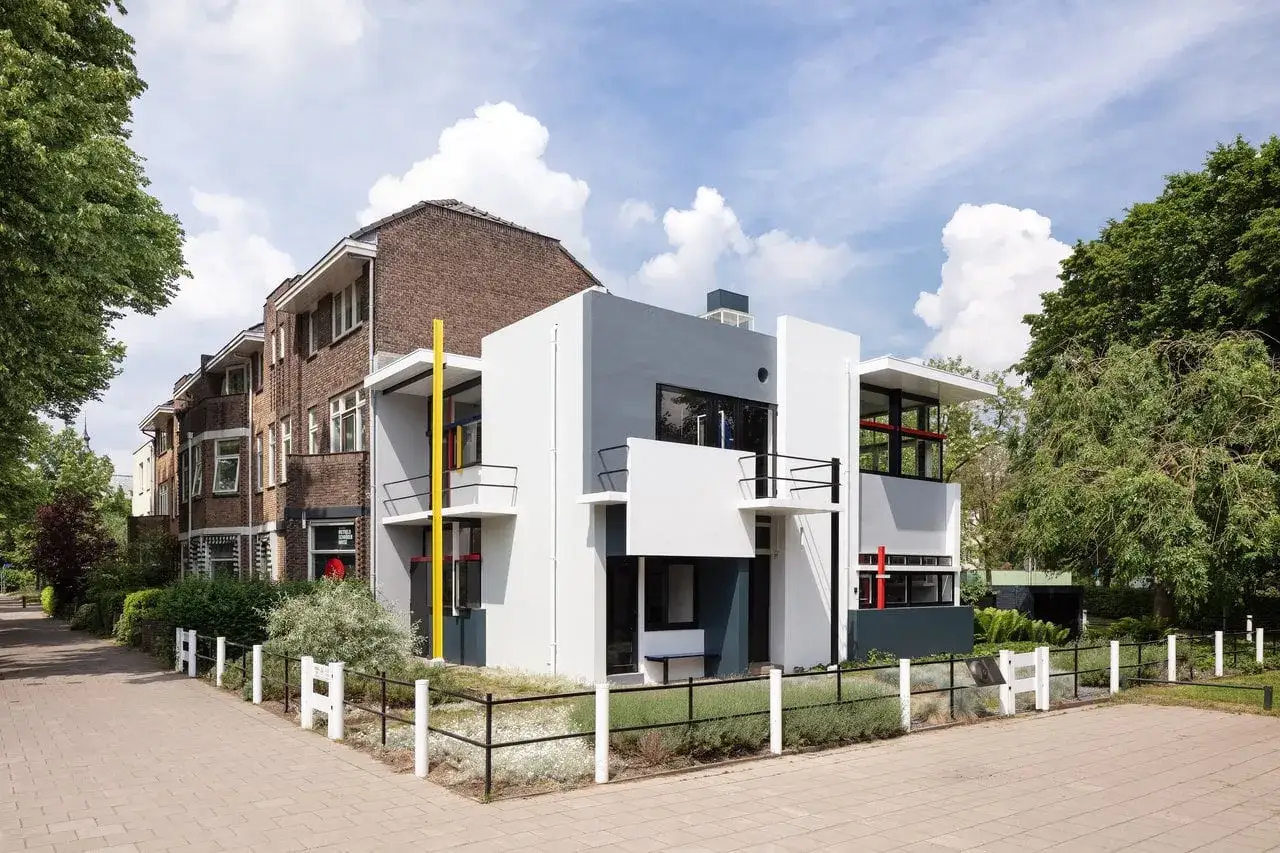 Moderne architectuur met strakke lijnen en contrasterende kleuren. Naast de witte en grijze volumes staan bakstenen gebouwen, wat zorgt voor een uniek contrast tussen oude en nieuwe, mooie gebouwen.