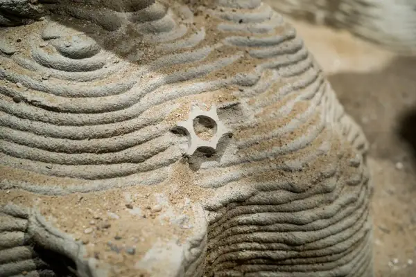 Gelaagde zand- en steenstructuren tonen prachtige patronen in de natuur, met een klein, stervormig object in het midden.
