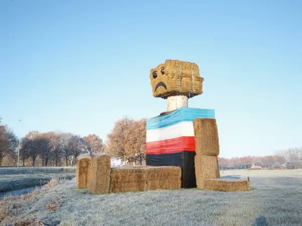 Een vrolijke, met stro gebouwde figuur met een verdrietig gezichtje, een kunstwerk van Henk Wildschut, staat in een winterse wei.