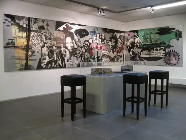 Een muurschildering met jazzmuzikanten en surrealistische elementen, mogelijk van Hans Truijen, in een galerie met barkrukken.