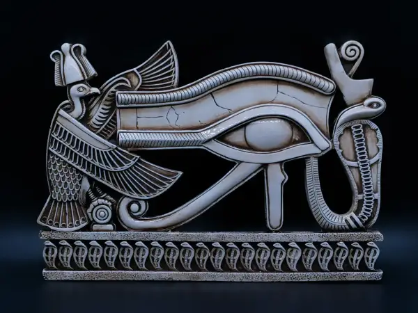 Een gedetailleerd beeld van het Oog van Horus, een symbool uit de Egyptische mythologie, met een vogelkop en slangen. Dit is een prachtig voorbeeld van oude bijbelse kunst.